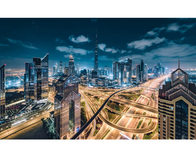 Beleuchtete Stadt bei Nacht mit Autobahnen durch die Landschaft.