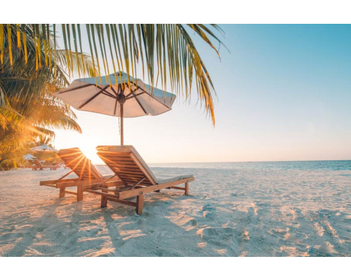 Fototapete von einem tropischen Strand bei Sonnenuntergang, mit Strandliegen mit Blick auf das ruhige Meer.