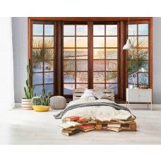Eine Fototapete mit 3D-Fensteransicht der Dünen, des Strandes und des Meeres in einem stimmungsvollen Schlafzimmer.