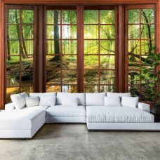 Eine Fototapete mit 3D-Fensteransicht einer sonnigen Waldlandschaft in einem gemütlichen Wohnzimmer.