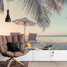 Eine lebendige Fototapete von einem tropischen Strand mit Liegestühlen und Palmen, perfekt für ein Wohnzimmer.