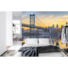 Eine Fototapete, die die Ben-Franklin-Brücke bei einem farbenfrohen Sonnenuntergang zeigt, angezeigt in einem Schlafzimmer.
