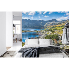 Eine Fototapete mit einem ruhigen Bergsee und Bergen, abgebildet in einem Schlafzimmer.