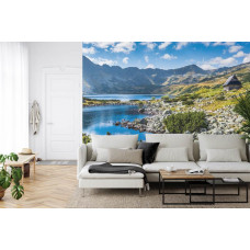 Eine Fototapete mit einem ruhigen Bergsee, umgeben von hohen Bergen, abgebildet in einem Wohnzimmer.