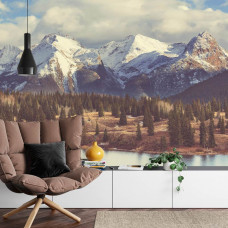 Eine Fototapete mit einem Panoramablick auf Berggipfel und einen üppigen Wald, perfekt für ein Wohnzimmer.