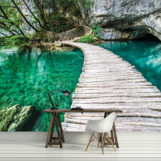 Eine Fototapete mit einer Holzbrücke über einen türkisfarbenen Teich, ideal für ein ruhiges Wohnzimmer.