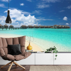 Eine Fototapete mit einer tropischen Malediven-Atmosphäre mit einem weißen Strand und blauem Meer in einem Wohnzimmer.