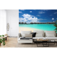 Eine Fototapete mit einem paradiesischen Strand und türkisfarbenem Meer der Malediven in einem Wohnzimmer.