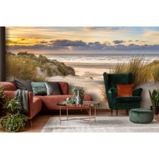 Fototapete mit den Dünen an der Nordsee mit einem Strand und einem schönen Sonnenuntergang, in lebendigen Farben in einem Wohnzimmer.
