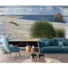 Eine Fototapete mit einer Strandlandschaft mit Dünen und Meer auf Holzplanken in einem Wohnzimmer.