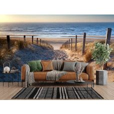 Fototapete mit einem Dünenpfad zum Meer an der Wand eines hellen Wohnzimmers mit natürlichen Farbtönen.