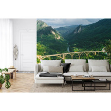 Eine Fototapete mit der Durdevica Tara-Brücke in Montenegro und den umliegenden Bergen, abgebildet in einem Wohnzimmer.