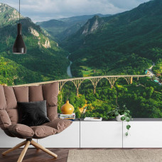 Eine Fototapete mit der Durdevica Tara-Brücke in einer Berglandschaft, abgebildet in einem Wohnzimmer.