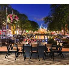 Fototapete mit einem roten Fahrrad auf einer Brücke bei Abenddämmerung in einem Esszimmer, wobei die beleuchteten Grachtenhäuser eine warme Atmosphäre schaffen.