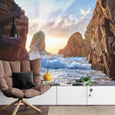 Eine Fototapete mit wilden Wellen, die gegen Felsen in einem von Bergen umgebenen Meer schlagen, perfekt für ein Wohnzimmer.