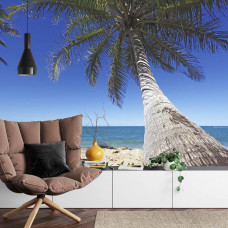 Eine Fototapete mit einer ruhigen Strandumgebung mit einer imposanten Palme in einem Wohnzimmer.