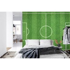 Eine Fototapete mit einem ausgestreckten Grasfeld und einem Fußball in einem Schlafzimmer.