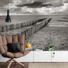 Eine Fototapete mit Holzpfählen an einem ruhigen Strand, perfekt für ein Wohnzimmer.