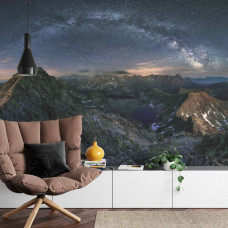 Eine Fototapete mit der Milchstraße und funkelnden Sternen über einer Berglandschaft, abgebildet in einem Wohnzimmer.