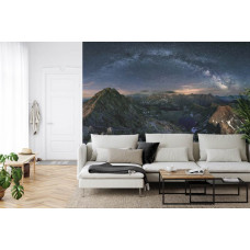 Eine Fototapete mit der Milchstraße über Bergen und einer hellen Sternenlandschaft, abgebildet in einem Wohnzimmer.