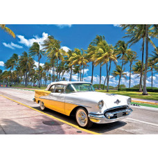 Fototapete mit einem gelb-weißen Oldtimer an einer sonnigen Promenade mit Palmen in Miami.