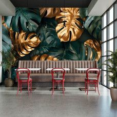 Fototapete mit Monstera Blättern und goldenen Details in einem Restaurant mit eleganter Atmosphäre.