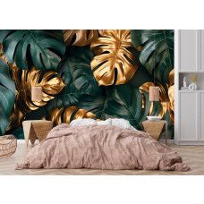 Fototapete mit botanischen Monstera Blättern und Goldakzenten an der Wand eines Schlafzimmers.