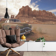 Eine rustikale Fototapete eines verlassenen Autos in einer felsigen Wüstenumgebung, ideal für ein Wohnzimmer.