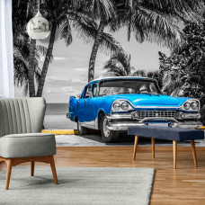 Fototapete eines alten blauen Autos mit Palmen und dem Meer in Kuba, geeignet für das Wohnzimmer.