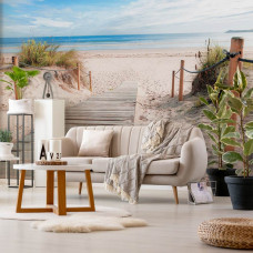 Eine Fototapete mit einem Weg zum Strand mit Meer und Dünen, geeignet für ein gemütliches Wohnzimmer.