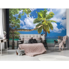 Eine Fototapete von einem Strand mit Palmen und blauem Meer im Schlafzimmer.