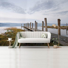 Eine Fototapete mit einem Steg am See in einer Landschaft, zu sehen im Wohnraum.