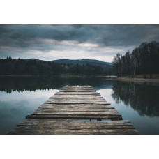 Fototapete von einem Holzsteg, der sich über einen ruhigen See erstreckt, umgeben von einer üppigen Naturlandschaft.