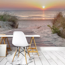 Fotobehang Romantische Zonsondergang aan het Strand in een kantoor, met een serene scène van een houten pad tussen de duinen en een zonsondergang boven de zee, perfect voor inspiratie en rust.