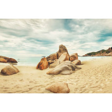 Fototapete mit Felsen am Strand, die sich zum Meer hin erstrecken, mit einer ruhigen und friedlichen Landschaft im Hintergrund.