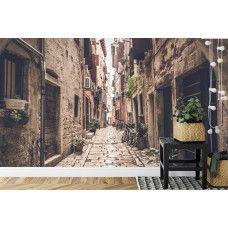 Eine Fototapete mit einer toskanischen Gasse, abgebildet in einem Schlafzimmer.