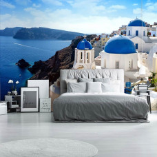 Eine Fototapete des ikonischen Santorin in Griechenland mit einer entspannenden Urlaubsatmosphäre im Vliestapetenstil für ein Schlafzimmer.