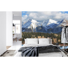 Eine Fototapete mit hohen Schneegipfeln über einem grünen Wald, ideal für ein Schlafzimmer.