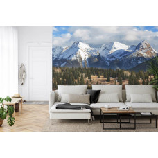 Eine Fototapete mit einem majestätischen Blick auf Schneegipfel und einen üppigen Wald, geeignet für ein Wohnzimmer.