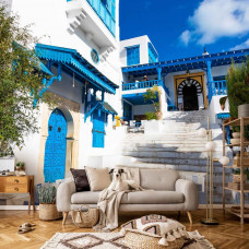 Eine Fototapete einer Straße in Tunesien, mit blauen Häusern und einer ruhigen Atmosphäre, geeignet für ein Wohnzimmer.