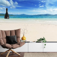 Eine schöne Fototapete mit einem Strand und Meer in Blautönen, ideal für ein Wohnzimmer.