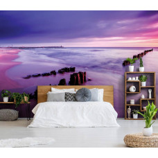 Fototapete, die einen Strand und einen violetten Himmel bei Sonnenuntergang zeigt, in einem Schlafzimmer.