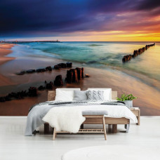 Eine Fototapete, die eine Strandlandschaft bei Sonnenuntergang und einen farbenfrohen Horizont zeigt.