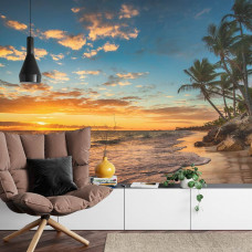 Eine Fototapete mit einer idyllischen Strandlandschaft mit Palmen bei einem farbenfrohen Sonnenuntergang, ideal für ein Wohnzimmer.