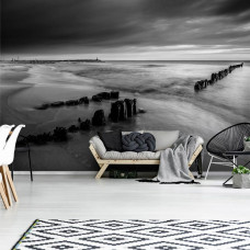 Eine Fototapete mit einem schwarz-weißen Strand bei Sonnenuntergang, mit Blick auf das Meer und den Himmel.