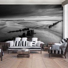 Eine Fototapete mit einer schwarz-weißen Strandlandschaft bei Sonnenuntergang im Wohnzimmer.