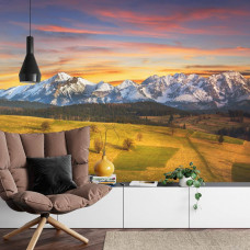 Eine Fototapete mit einem Sonnenuntergang über dem Tatra-Gebirge in einem Wohnzimmer.
