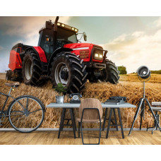 ein mächtiger Traktor macht Strohballen auf einem Feld.