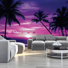 Eine Fototapete mit einem tropischen Sonnenuntergang am Meer mit Palmen, sichtbar in einem Wohnzimmer.