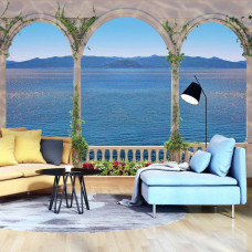 Eine Fototapete von einem griechischen Balkon mit Meerblick im Wohnzimmer.